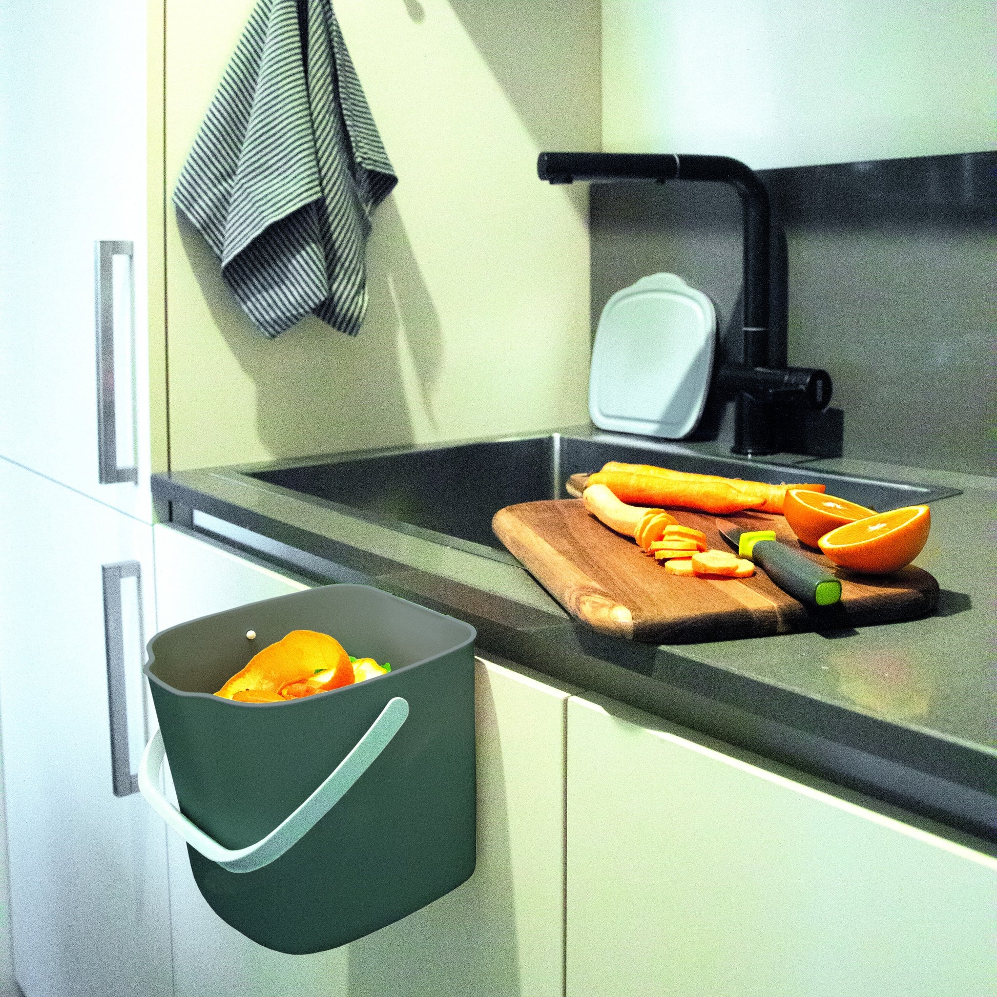 Cubo orgánico ImpakCity colgante en encimera de cocina junto a vegetales frescos